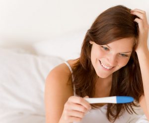 Woman holding positive pregnancy test