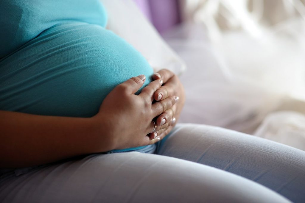 Pregnant woman hands gently clasped over belly