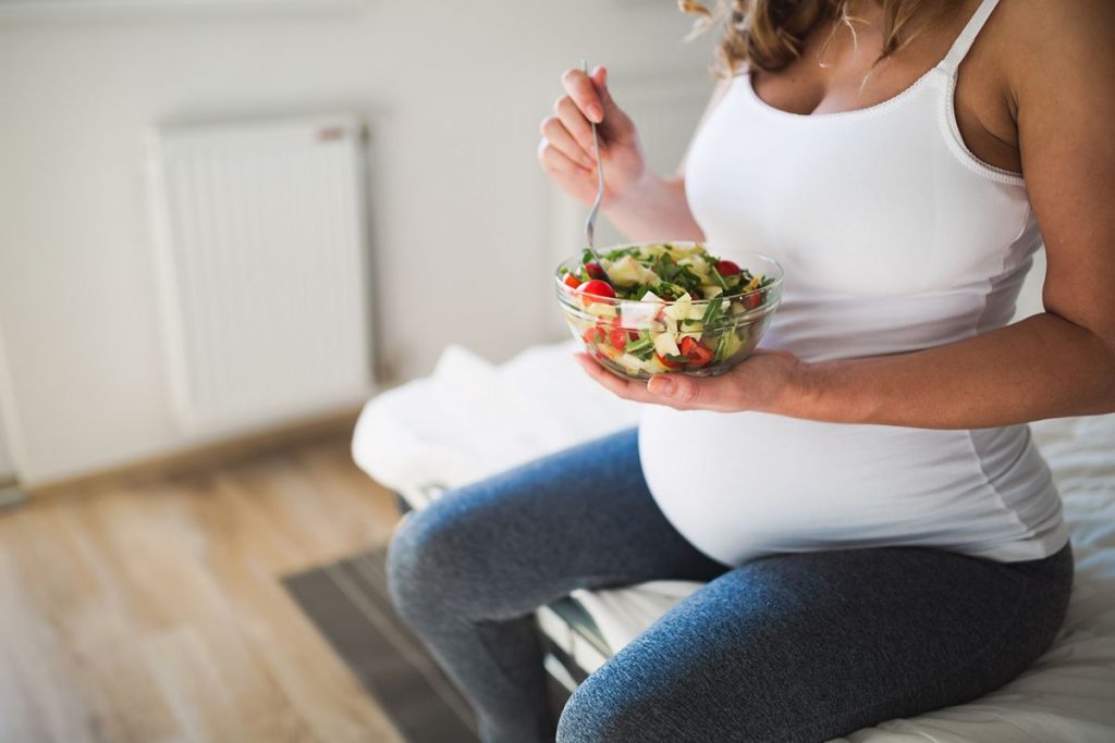 Pregnant woman eating salad, acupuncture during pregnancy. 