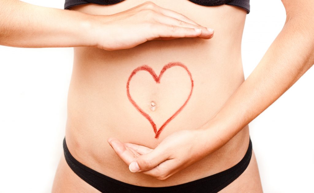 Hands over love heart on female tummy